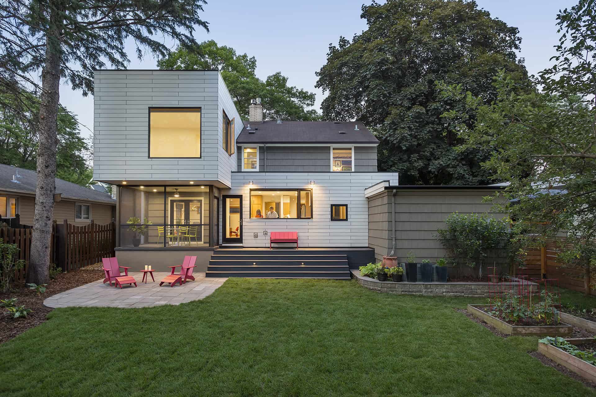 Types of Home Additions to Consider 3 Back exterior of house showing new metal clad addition with portions of original parts of house visible with mother and daughter in window